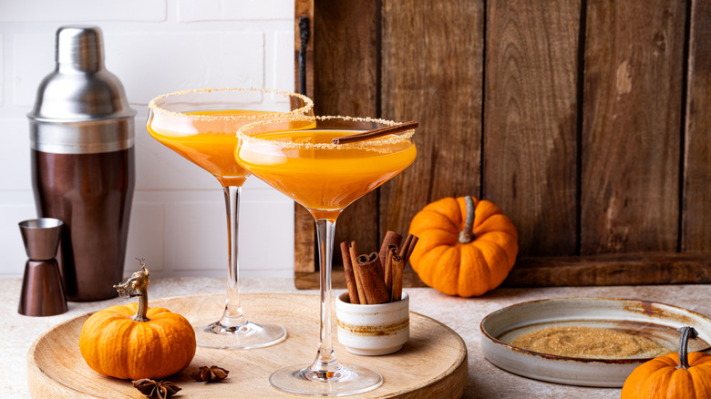 Two pumpkin martinis with some pumpkin decorations on the side