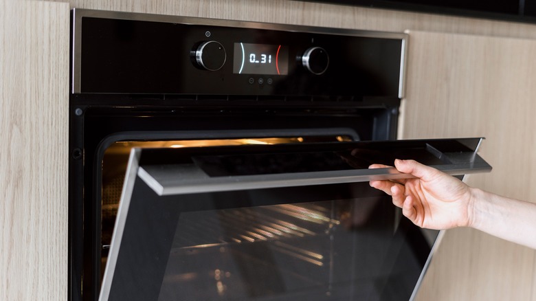 Hand slightly opening oven door