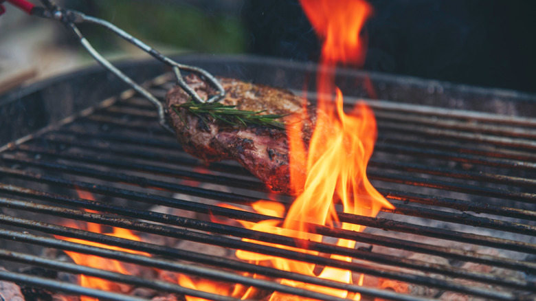 Steak being grilled over charcoal fire