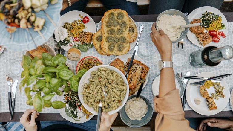 overhead view of a crowded dinner party table with appetizers and drinks