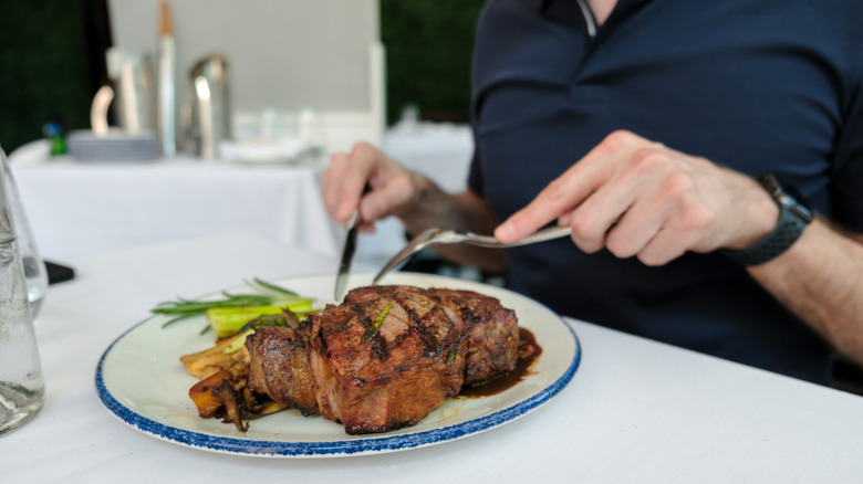 person sitting in restaurant eating a steak