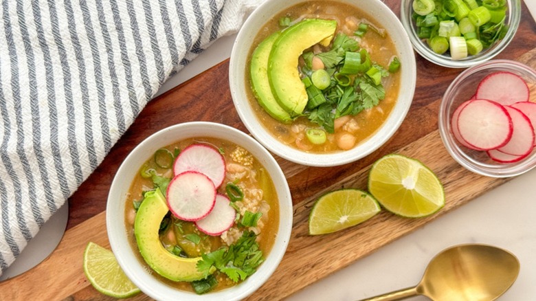 Bowls of tomatillo and white bean chili with avocado, spring onion, and radishes