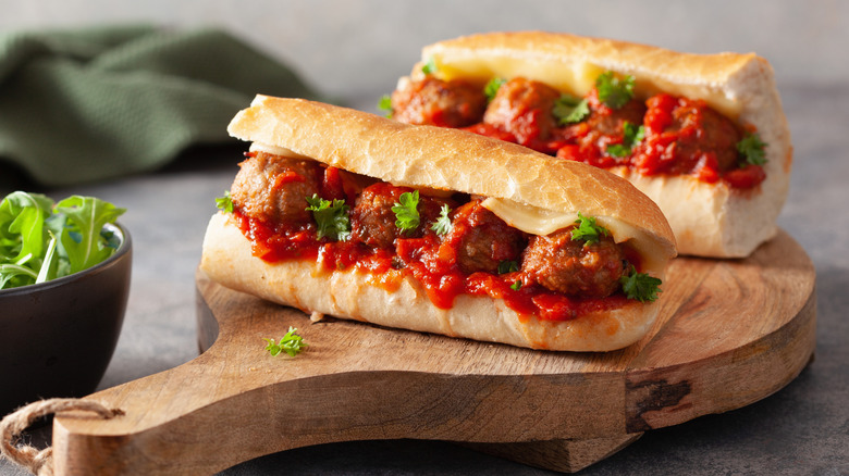 Two halves of a meatball sub on a wooden board