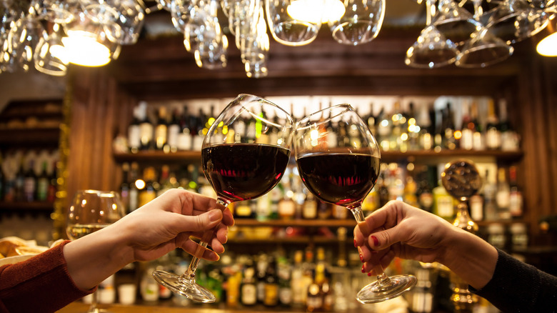 Two women toasting with glasses of wine in a cozy, cheerful wine bar