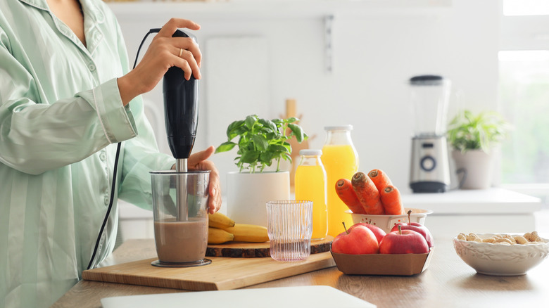 someone making smoothie at home with ingredients in kitchen