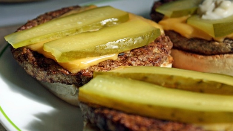 Sliced pickles on top of cheeseburgers