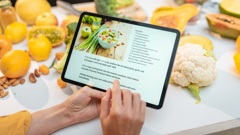 hands scrolling through a recipe on an ipad