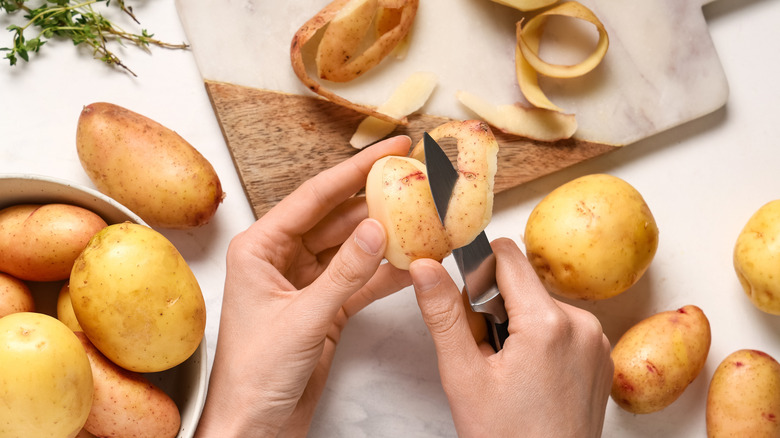 Close-up of hands peeling potatoes