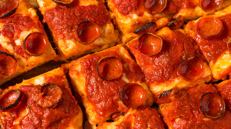 Detroit-style pizza cut into squares on a wooden board