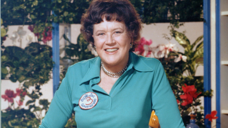 Julia Child wearing green shirt in front of plants and flowers