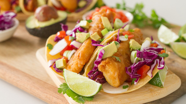 A plate of fish tacos garnished with salad