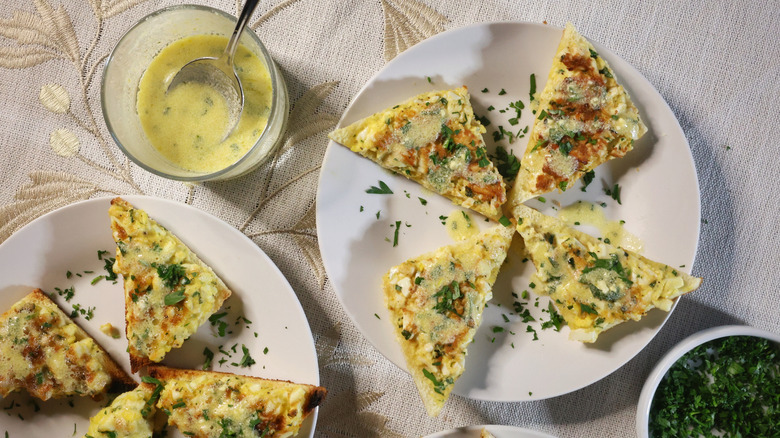 overhead view of plates of egg toasts with dishes of parsley and vinaigrette beside them