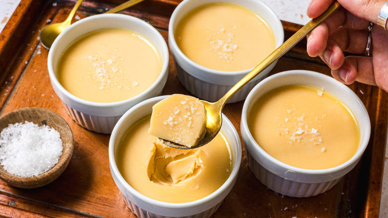 Taking a spoonful out of a ramekin of salted caramel panna cotta