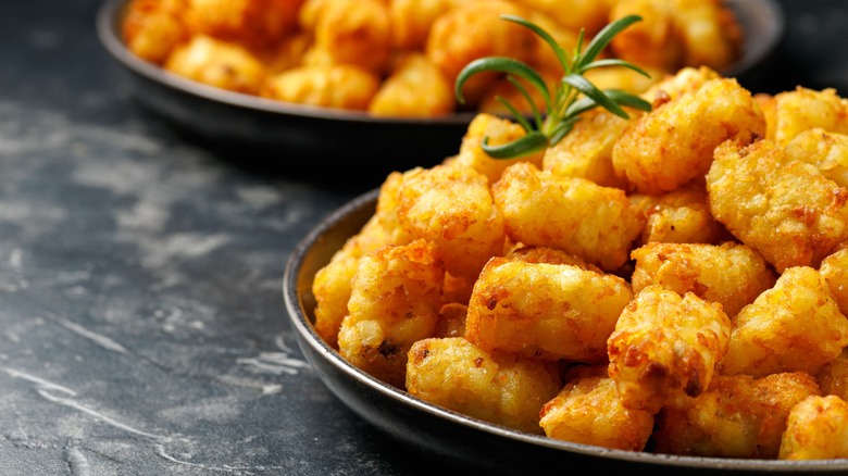 bowls of crispy fried tater tots on a black background