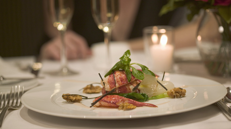 The refined looking plate with lobster meat and some micro greens in an upscale setting