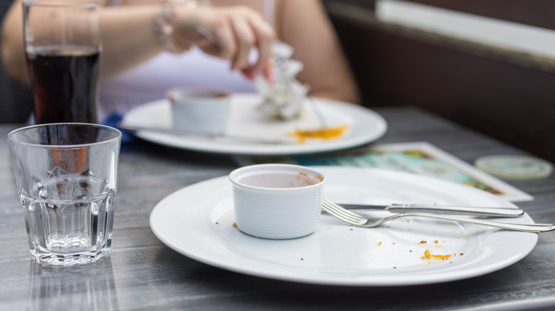 Empty plates on table with person sitting in background