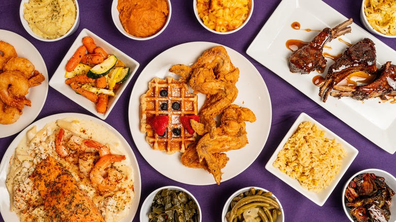 Assortment of soul food dishes including chicken and waffles, rice, and mac and cheese on purple tablecloth