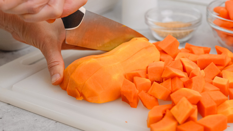person cutting butternut squash on board