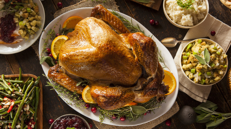 Top-down shot of a Thanksgiving turkey on a white platter surrounded by side dishes