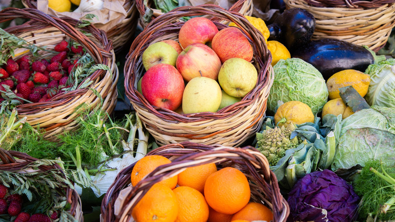 A large spread of fruits and vegetables including apples, oranges, strawberries, cabbage, lemons, eggplant, and more