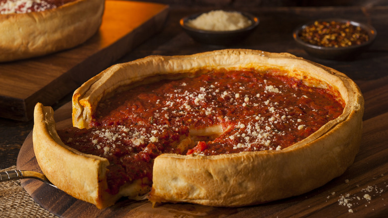A slice is taken from a deep dish pizza on a table at Lou Malnati's