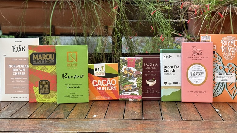 Nine bars of chocolate in packaging standing vertically on wooden table