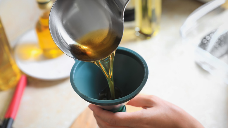 Person pouring oil into funnel