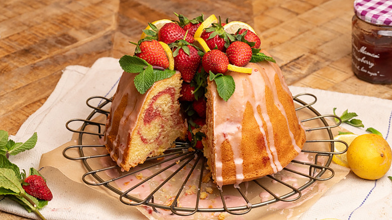 Sliced strawberry lemonade bundt cake topped with fresh strawberries, mint leaves, and lemon slices