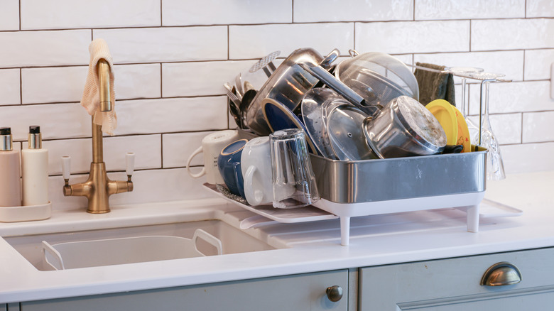 drying rack overflowing with dishes on kitchen counter
