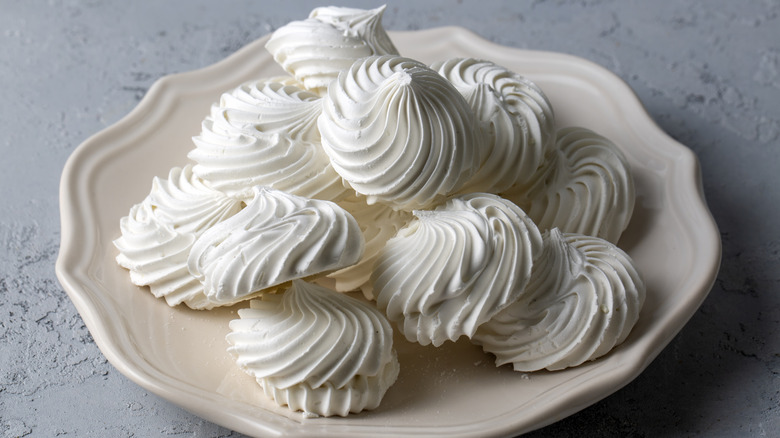 meringue cookies piled on an ivory plate