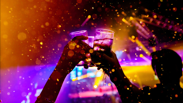 Hands clinking glasses together at dance party