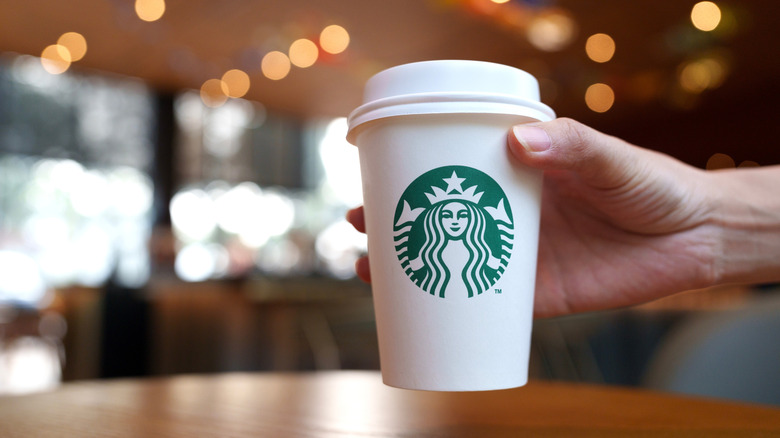 hand holding a Starbucks coffee cup with logo inside store
