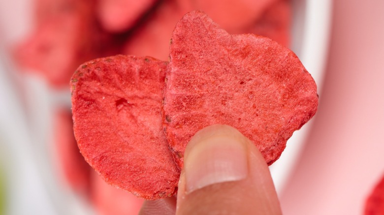 person holding 2 slices of freeze-dried strawberries