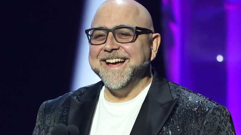 Duff Goldman smiles on stage with black framed glasses