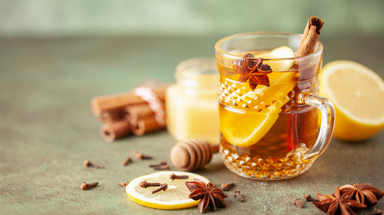 Hot toddy with lemons, cinnamon sticks, honey dipper