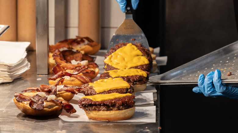 Bacon cheeseburgers being Prem pared by employee