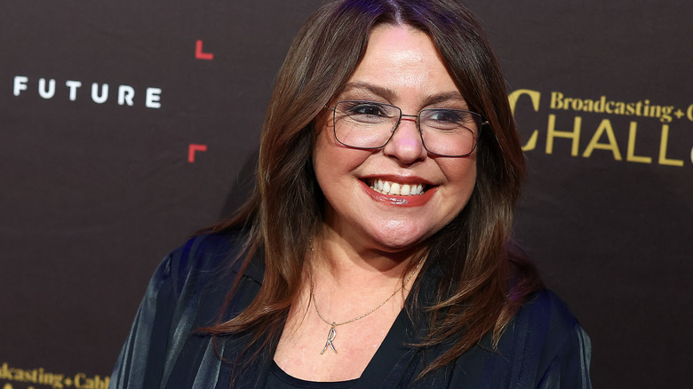 Rachel Ray smiling in a navy outfit with glasses