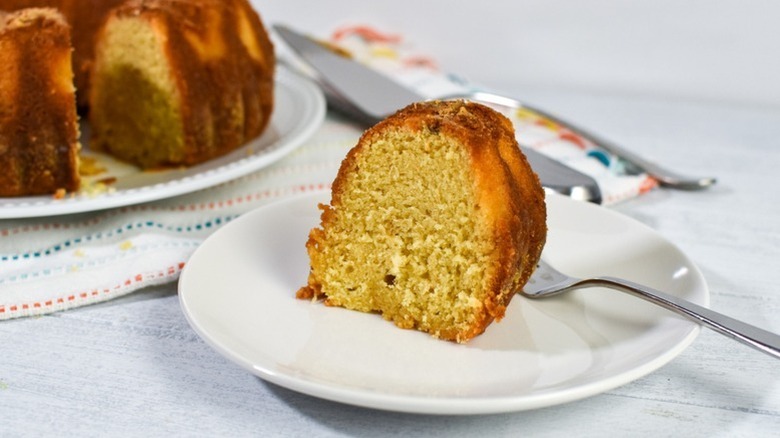 Slice of rum bundt cake on white plate with fork
