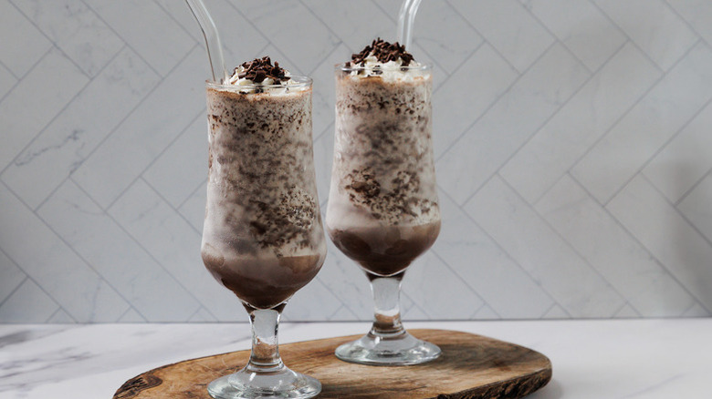 Two chocolate cocktails in glasses garnished with whipped cream and chocolate shavings