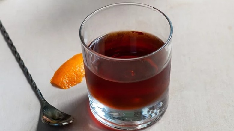 Manhattan drink beside spoon and orange peel