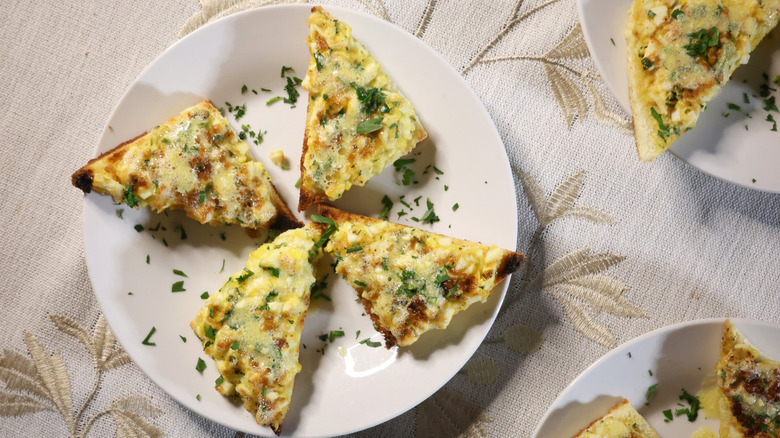 an artfully arranged plate of four egg toasts garnished with minced parsley