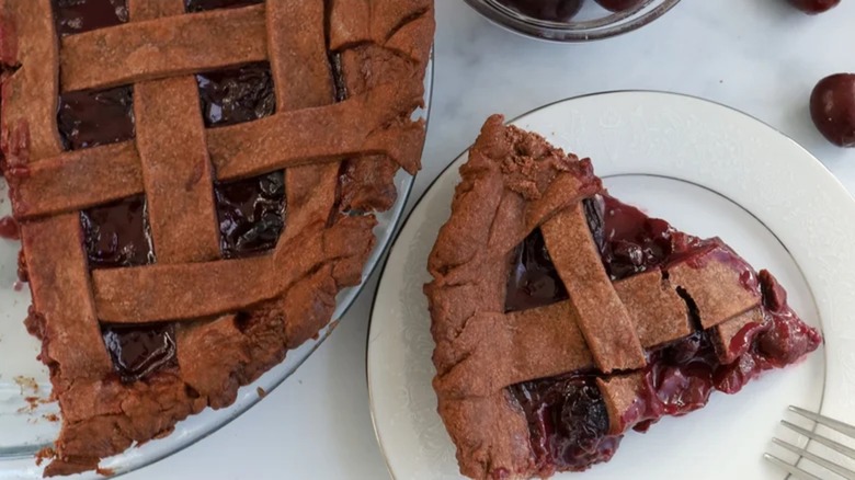 Slice of Pomegranate cherry cocoa pie on plate next to the rest of the pie