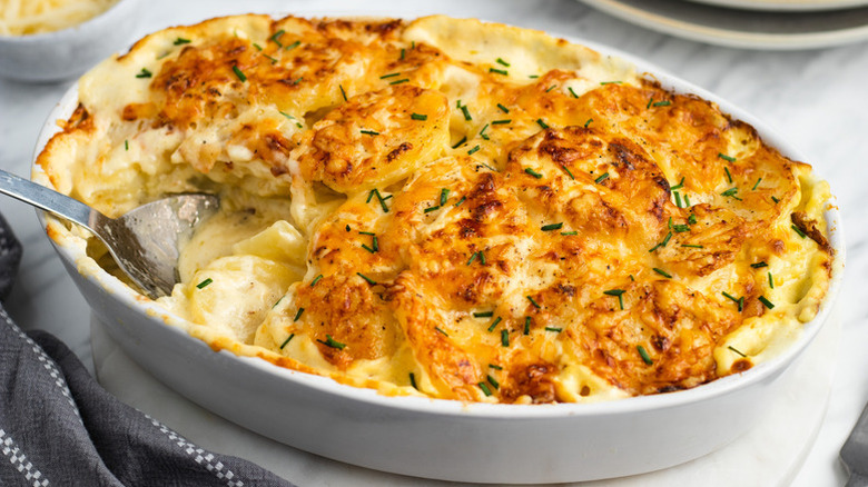 Potatoes au gratin in baking dish with spoon
