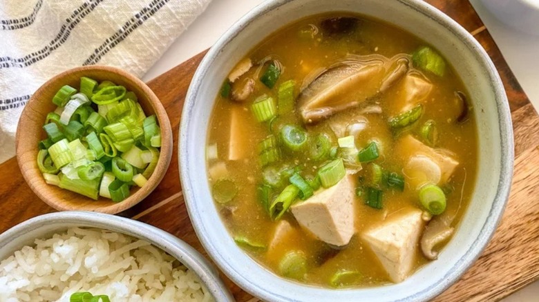 Miso soup in bowl with green onions and rice adjacent