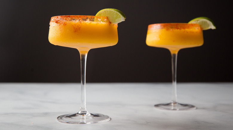 Frozen mango cocktails in glasses with lime wedge garnish