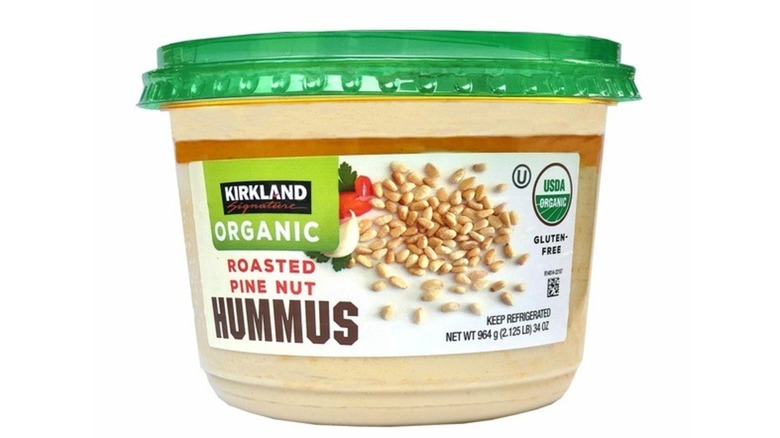 Large, round tub of hummus with images of pine nuts and garlic on exterior