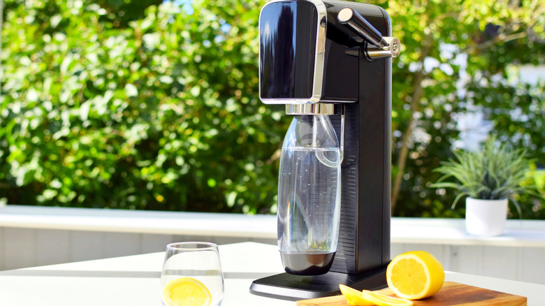 SodaStream machine in outdoor kitchen next to halved lemon on wooden cutting board