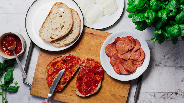 Two bread pieces with marinara sauce on cutting board