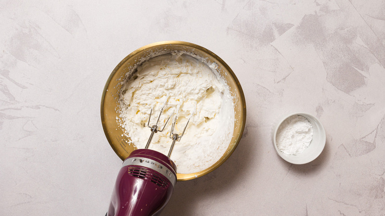 Whipped cream in bowl with electric beater