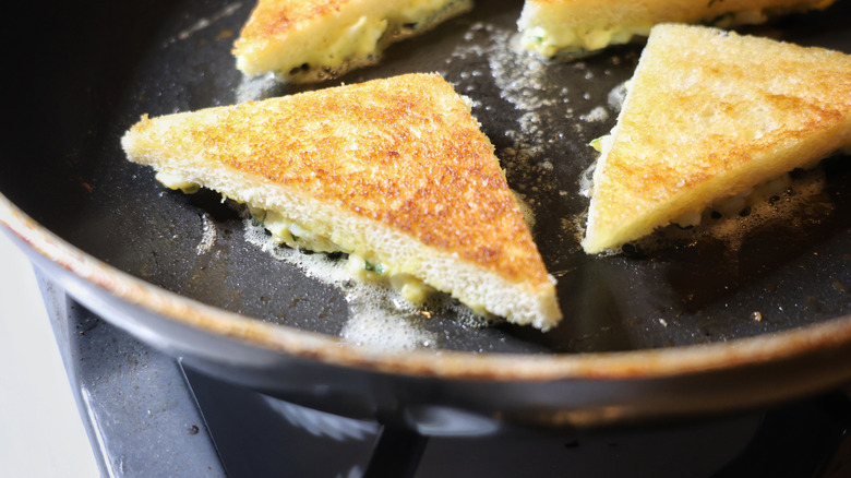 egg toasts frying egg-side-down in a buttery skillet